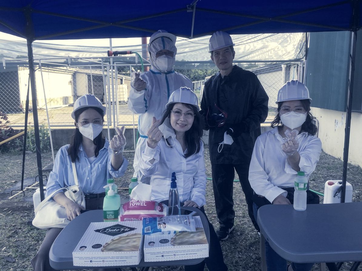 Visitors in hard hats at a check-in table under a tent